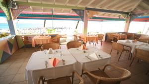 un restaurante con mesas y sillas blancas y el océano en Timothy Beach Resort, en Frigate Bay