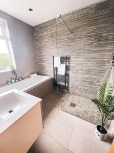 een badkamer met een bad, een wastafel en een douche bij Beechwood Park by Solace Stays in Newport