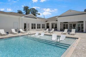 a swimming pool with white chairs and a house at Tranquil Serenity - Exchange at Orange Park in Jacksonville