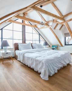 ein großes weißes Bett in einem Zimmer mit großen Fenstern in der Unterkunft Casa dintre dealuri in Rozavlea