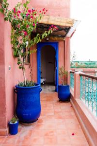 2 macetas azules grandes con flores en el balcón en Riad Bianca Marrakech, en Marrakech