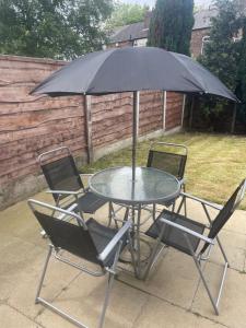 a table with two chairs and an umbrella at Beautiful 4 bed home, Sleeps 8, driveway parking, With sky & BT sports in Manchester