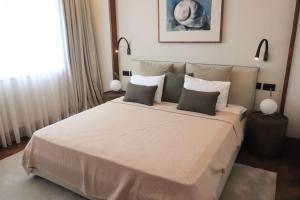 um quarto com uma grande cama branca e 2 almofadas em Luxury One bedroom apartment Elena Porto Montenegro em Tivat