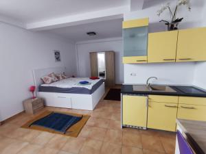 a bedroom with a bed and a kitchen with yellow cabinets at Fitness House with garden in Constanţa