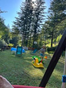 una niñita jugando en un tobogán en un patio de juegos en Apartmaji in Sobe Cuder, en Soča