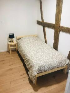 Cama pequeña en habitación con suelo de madera en Les Lavandières Scherwiller, en Scherwiller