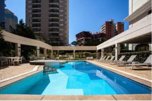 a large swimming pool with chairs and a building at Apartamento 1912 World Vila Olímpia in Sao Paulo