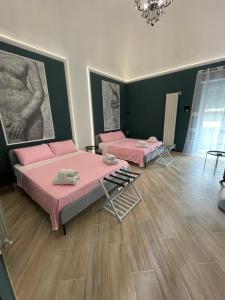 two beds in a room with pink sheets at La corte di poppea in Torre Annunziata