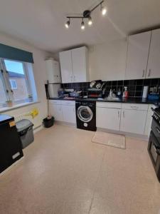 a kitchen with white cabinets and a washing machine at Room in a shared Flat in London