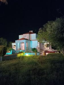 a large white house with a yard at night at Paradiso Kallithea villa in Koskinou