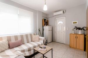 a living room with a couch and a table and a refrigerator at Hermes Modern Apartment in Alexandroupoli