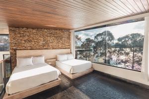 Luxé Cabañas في غواتابيه: غرفة نوم بها سريرين ونافذة كبيرة
