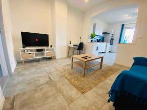 a living room with a couch and a tv and a table at L’escale Abbevilloise by H2C in Abbeville