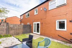 a patio with a glass table and chairs in front of a brick building at Mordenised 2 Bedroom House close to City Centre in Leeds