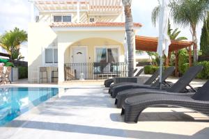 eine Villa mit einem Pool und Liegestühlen in der Unterkunft Sunset Villa private complex heated pool in Ayia Napa