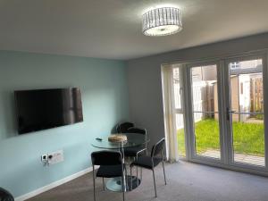 a dining room with a table and chairs and a tv at 3 bed house with parking near airport in Edinburgh