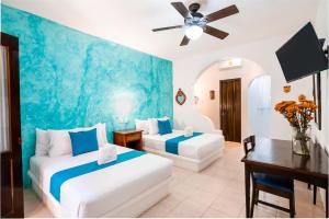 a hotel room with two beds and a table and a couch at Hotel Casa de las Flores in Playa del Carmen