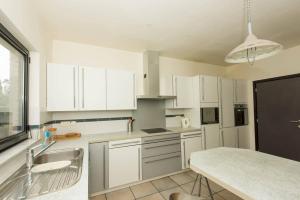 a kitchen with white cabinets and a sink and a counter at Vakantiehuis Villa 1 - 11 beds, 17p, 2 Bath-, 1 Livingroom in Houthalen-Helchteren