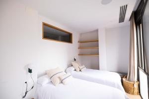 dwa białe łóżka w białym pokoju z telewizorem w obiekcie Apartamento ático en el casco antiguo w mieście Mataró