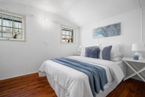 a white bedroom with a bed and a window at Seaside Chalet Papamoa in Papamoa