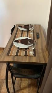 a wooden table with two wine glasses and a plate at Suíte Boqueirão Tati Ortega in Ilha Comprida