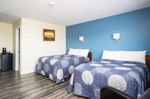 Habitación con 2 camas, paredes azules y suelo de madera. en Hebridean Motel en Port Hood