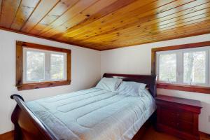 1 dormitorio con 1 cama y 2 ventanas en Belmont Beach Cottage, en West Harwich