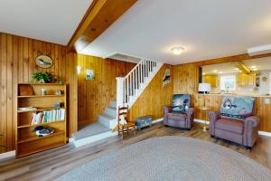 uma sala de estar com paredes de madeira e escadas com duas cadeiras em Cobbossee Hideaway em Winthrop