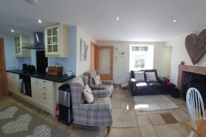 a living room with two couches and a kitchen at Strathken Cottage in Castle Douglas