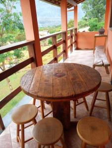 einen Holztisch und Stühle auf einem Balkon mit Aussicht in der Unterkunft Pouso dos Sonhos Suítes Lapinha da Serra in Santana do Riacho