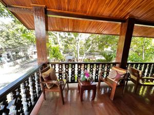 a porch with chairs and a table with flowers on it at Ammata Boutique Villa in Luang Prabang