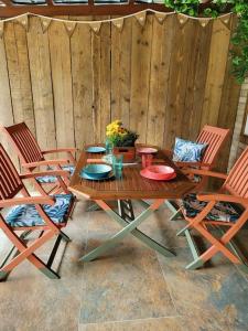 uma mesa de madeira e quatro cadeiras e uma cerca de madeira em DOG FRIENDLY little bungalow with patio & private driveway em Kessingland