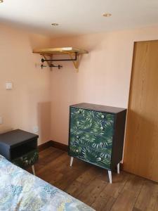 a bedroom with a bed and a dresser and a shelf at DOG FRIENDLY little bungalow with patio & private driveway in Kessingland