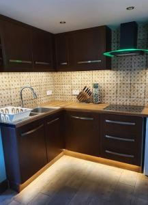 a kitchen with wooden cabinets and a sink at DOG FRIENDLY little bungalow with patio & private driveway in Kessingland