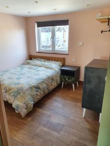 a bedroom with a bed and a table and a window at DOG FRIENDLY little bungalow with patio & private driveway in Kessingland