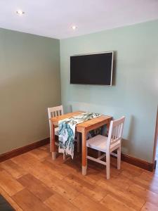 a dining room table with two chairs and a television at DOG FRIENDLY little bungalow with patio & private driveway in Kessingland