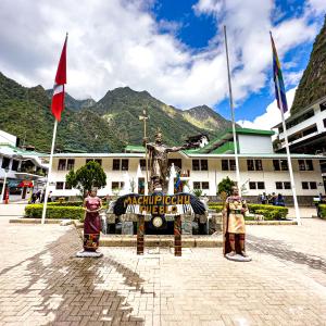 a building with flags and a statue in front of it at MACHUPICCHU BOUTIQUE in Machu Picchu