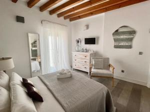 een witte slaapkamer met een bed en een stoel bij El 1 de Amador de los Rios in Toledo