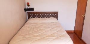 a bed in a small room with a white blanket at A un minuto del aeropuerto Siéntase como en casa in Cusco