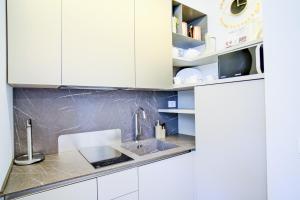 una cocina con armarios blancos y fregadero en Dolcevita Boutique Apartment, en Florencia