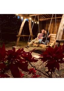 un hombre y una mujer sentados en un columpio en Casa Viva Alojamiento Rural en Jardin
