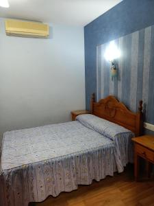 1 dormitorio con 1 cama y una luz en la pared en Restaurante & Hostal El Volante, en Moraleja