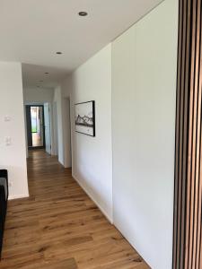 um corredor vazio com paredes brancas e pisos de madeira em Haus Am Anger Dornbirn em Dornbirn