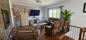 a living room with two chairs and a television at Superbe propriété moderne en nature in Sainte Brigitte de Laval