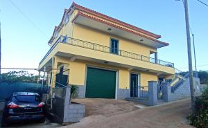a yellow house with a car parked in front of it at A Toca in Santana