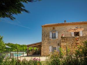 an external view of a stone house with an umbrella at Maison Girou Haut in Montcabrier