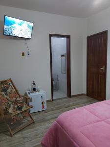1 dormitorio con 1 cama, 1 silla y TV en Recanto Casa Amarela, en Miguel Pereira