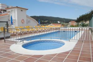 einen Pool mit Stühlen und einem Zaun in der Unterkunft Hotel Riveiro in Sanxenxo