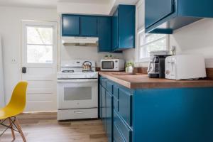 a kitchen with blue cabinets and a white stove top oven at Retro Retreat renovated 2BR, desk, no chore list! in Kingston