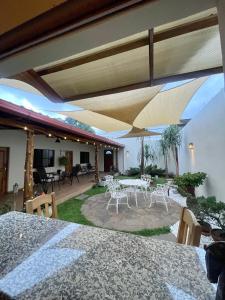 une terrasse avec des tables blanches, des chaises et des parasols dans l'établissement Hostal DEYLUWIN, à Juayúa